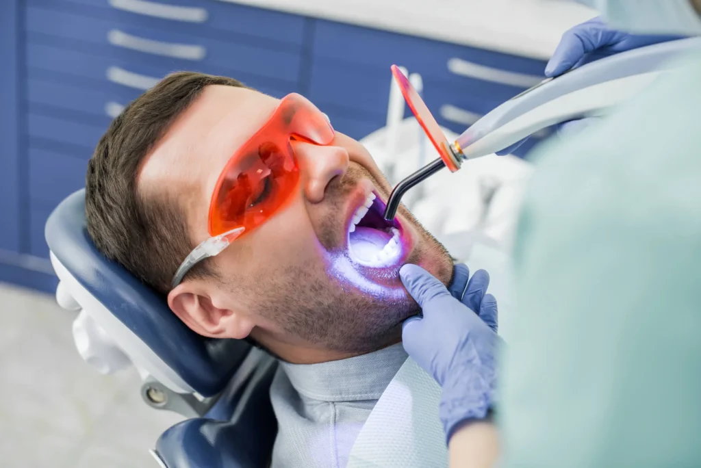 Male patient undergoing professional UV light teeth whitening procedure at dental clinic for a brighter smile. Teeth whitening in Pembroke Pines