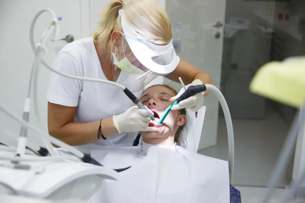 Dental hygienist cleaning patient’s teeth carefully dentist in Miramar